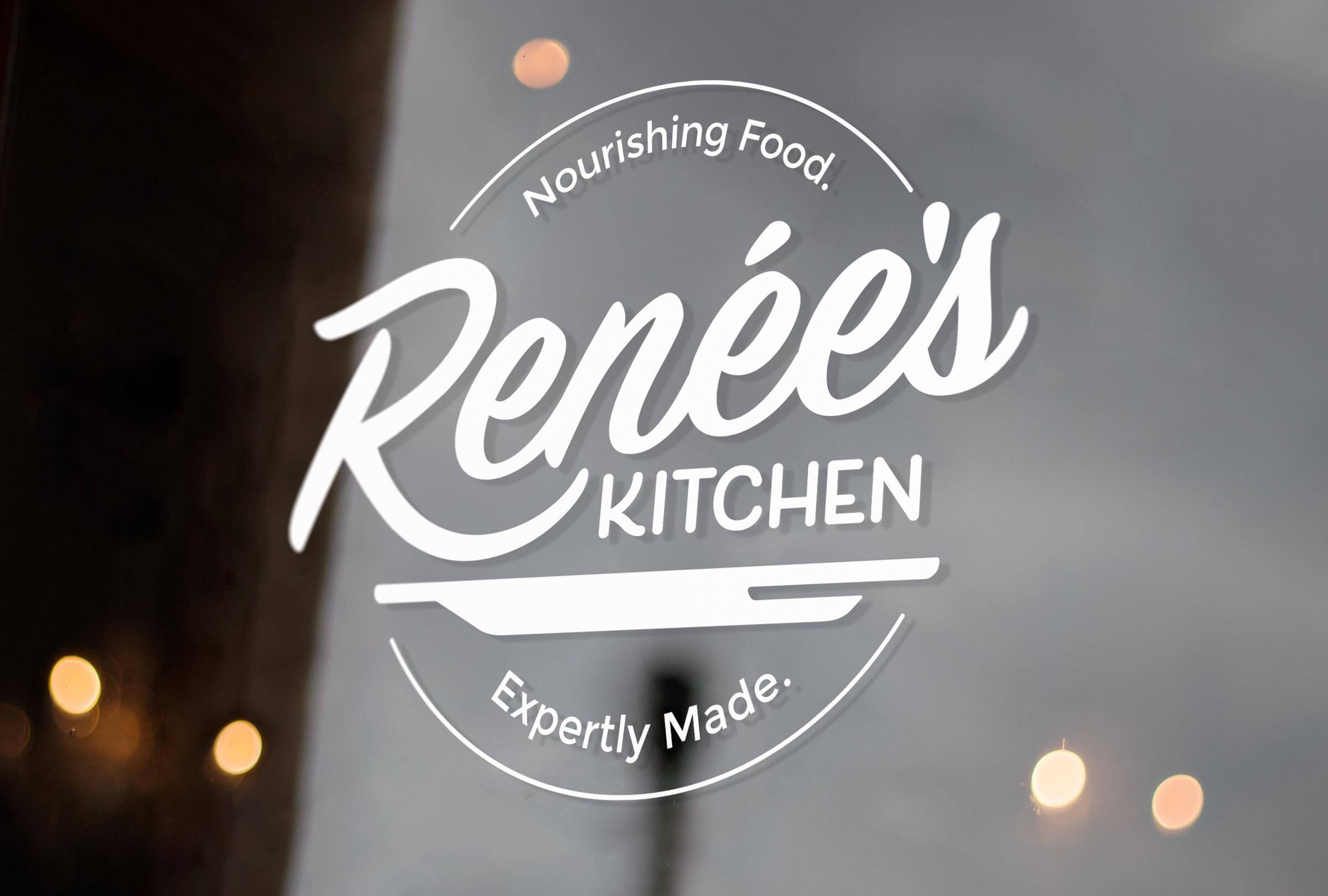 Mockup of the Renee's Kitchen logo on a window.